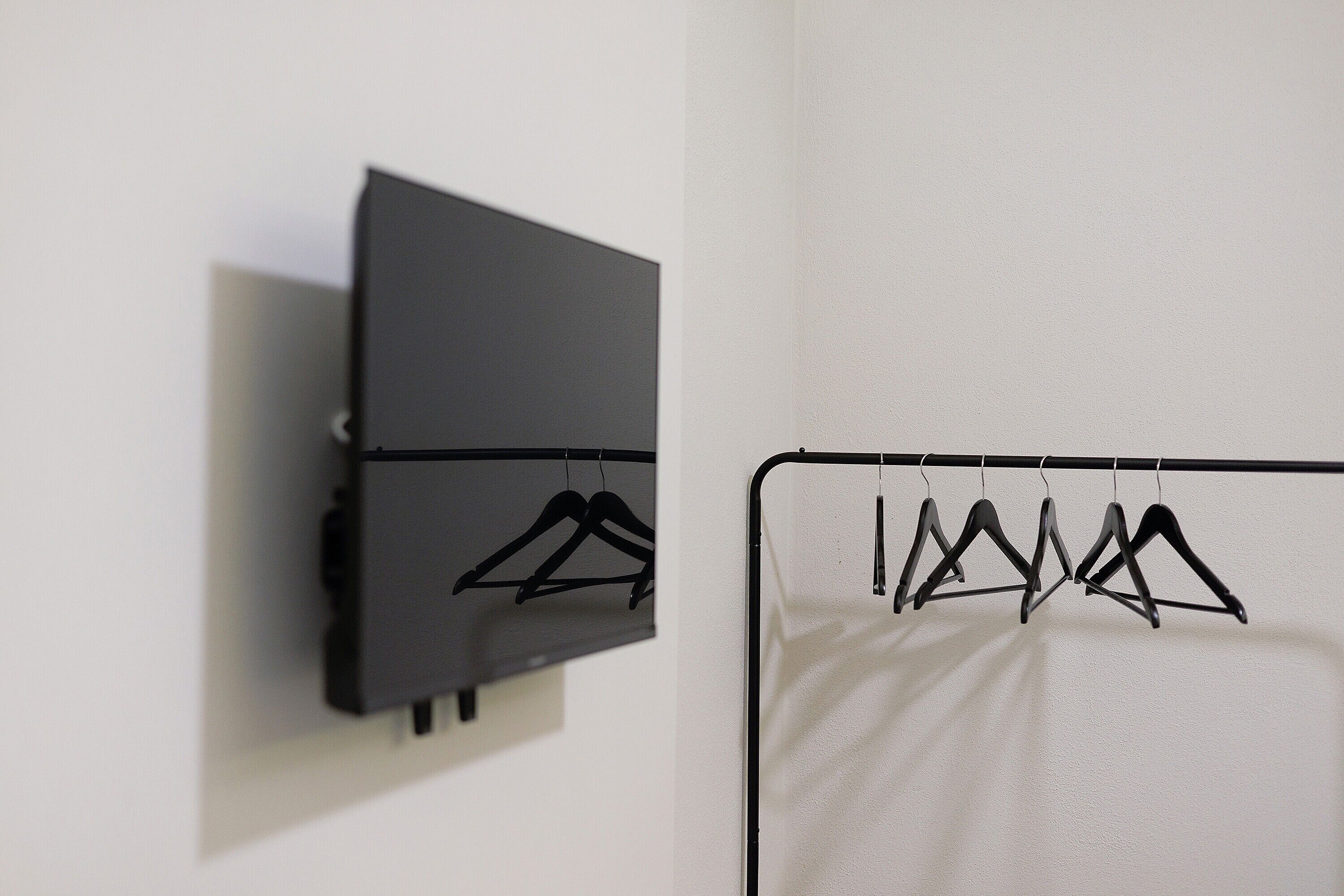 A wall-mounted black cabinet and a white fabric hanging on a black metal rack.