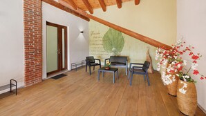 A room with a wooden ceiling, brick wall, and a large green leaf mural. There are four chairs, a table, and two large vases with flowers. - Farmhouse 'Al Campo Del Nocciolo Agriturismo' with Mountain View, Wi-Fi and Air Conditioning (Busca)