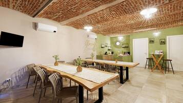 A dining area with brick ceiling, wooden tables, and chairs, and a green accent wall.