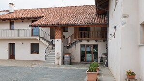 A two-story building with a tiled roof, a balcony, and a staircase leading to the upper floor. - Farmhouse 'Al Campo Del Nocciolo Agriturismo' with Mountain View, Wi-Fi and Air Conditioning (Busca)