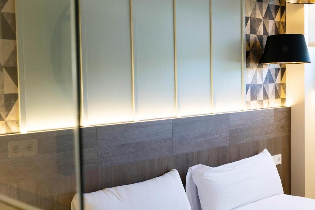 Een hotelkamer met een bed, een muur met geometrische patronen en een lamp.