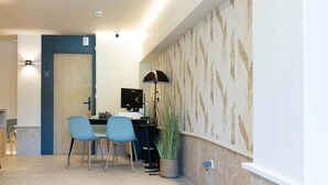 A modern hotel room with a desk, two chairs, a computer, and a decorative wall. - Urbaia Rooms (San Sebastian)
