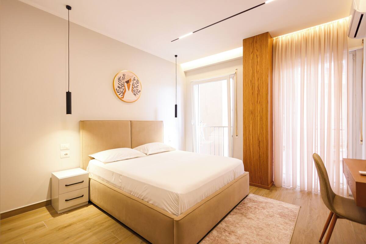 Um quarto moderno com cama, mesas de cabeceira, escrivaninha e uma cadeira.