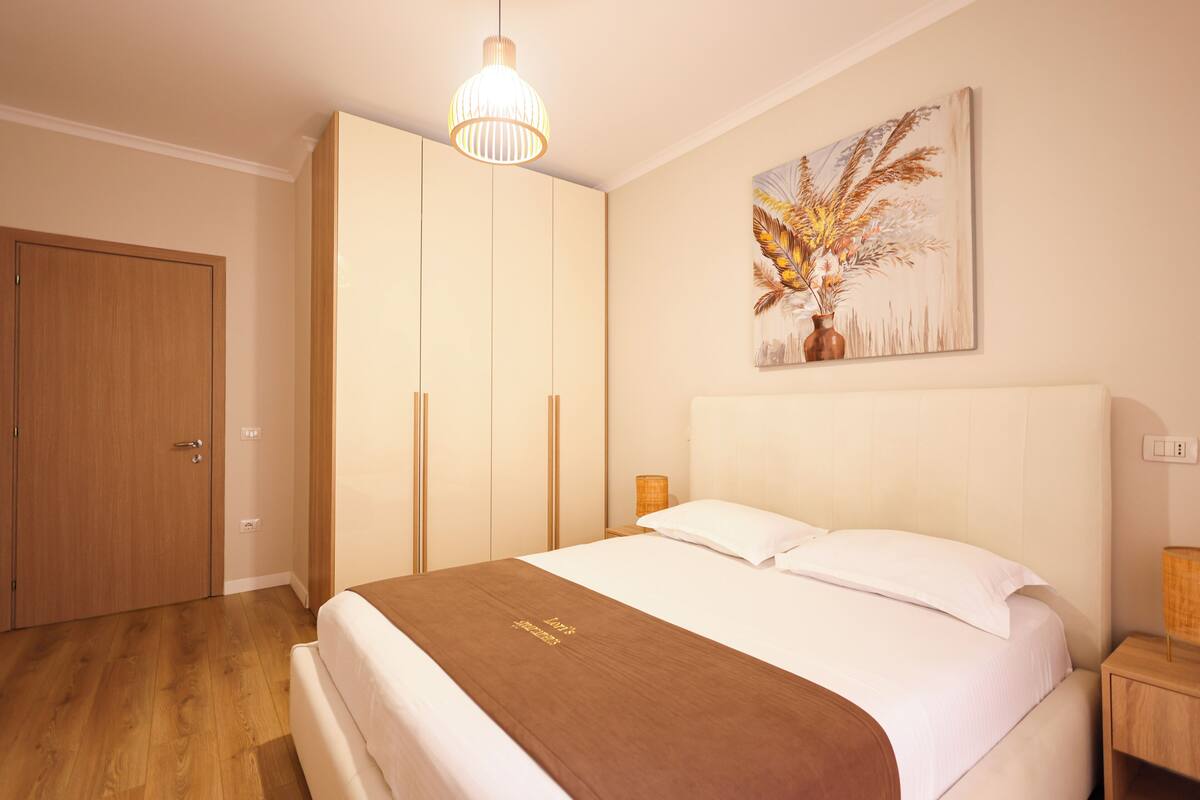 Quarto com cama, guarda-roupa de madeira e um quadro na parede.