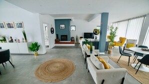Un salon moderne avec une cheminée, un canapé, une table à manger et des chaises.