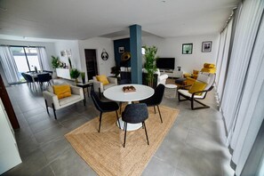 Ein modernes Wohnzimmer mit Essbereich, Fernseher und großem Fenster.