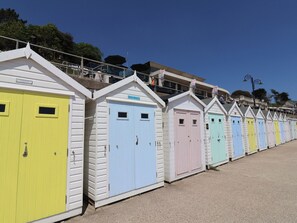 Eine Reihe bunter Strandhäuser mit weißen Fassaden und unterschiedlich farbigen Türen.