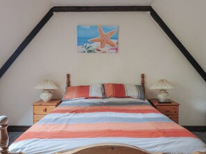 A bedroom with a sloped ceiling, a bed with striped bedding, two bedside lamps, and a starfish painting on the wall. - Cider House - Near Lyme Regis (Axminster)