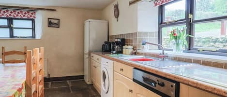 A compact kitchen with a washing machine, a coffee maker, and a sink.