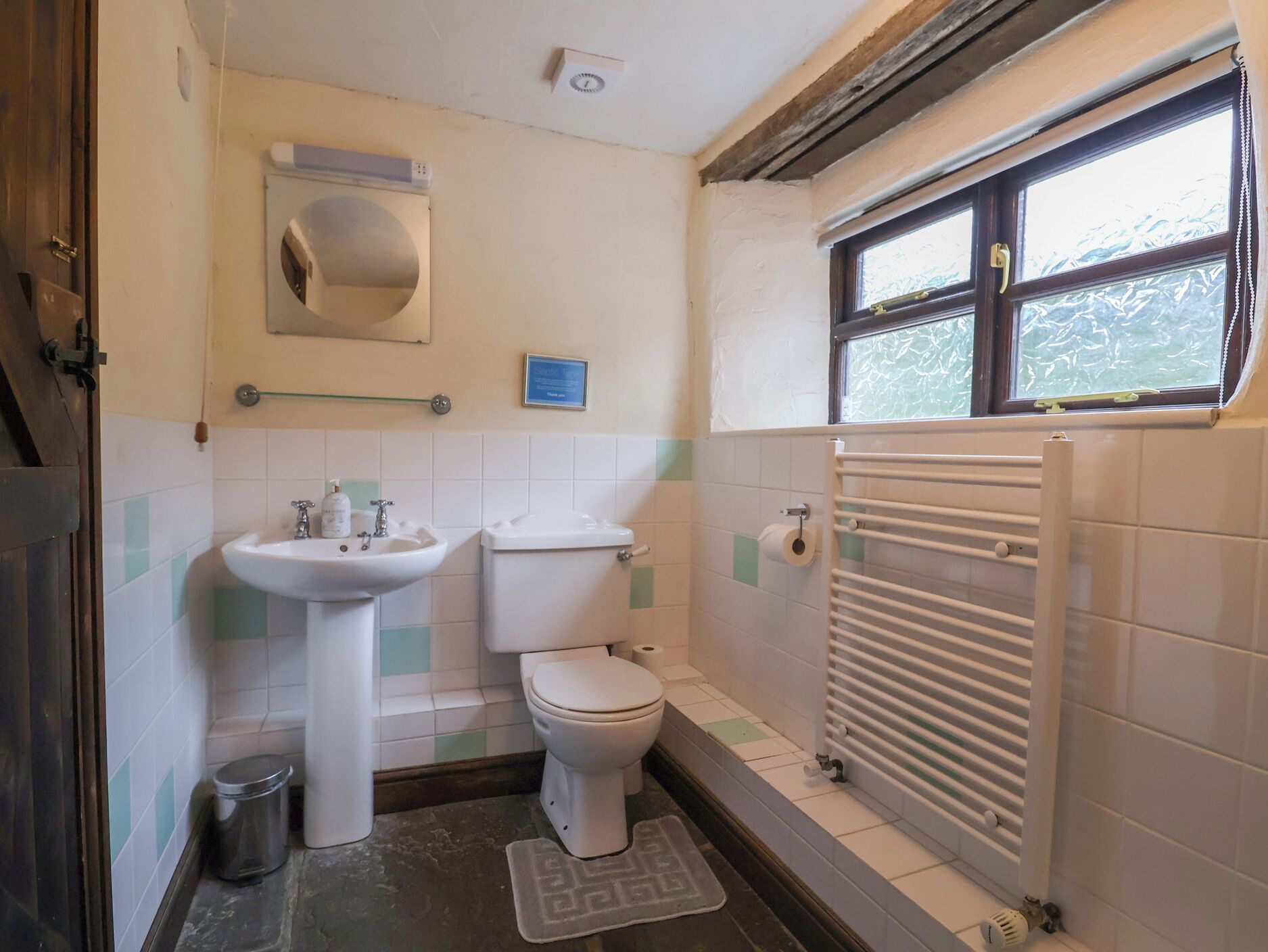 A small bathroom with a toilet, sink, and radiator.
