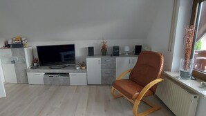 Un espai vital reduït amb televisió, armaris, una cadira i un radiador.