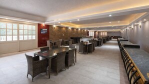 A spacious restaurant with high ceilings, multiple dining tables, and chairs. - DLS Tehri Club Resort (Tehri)