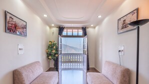 A hotel lobby with two sofas, a decorative plant, a view through a window, and artwork on the walls. - DLS Tehri Club Resort (Tehri)