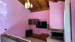 A living room with a wooden ceiling, a sofa, a TV, and a fireplace. - VILLA PAOLA L'AQUILA (Abruzzo)