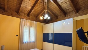 A bedroom with a wooden ceiling, a bed, a wardrobe, and a crib. - VILLA PAOLA L'AQUILA (Abruzzo)