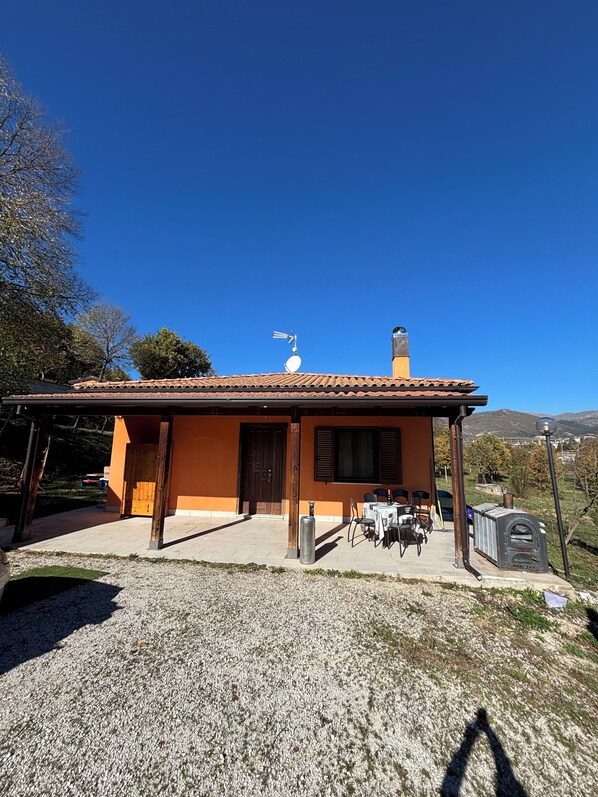 A single-story house with a tiled roof, a chimney, and a satellite dish.
