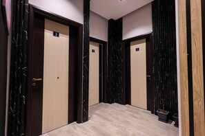 A hallway with three doors, each marked with a number. The doors are wooden with a marble-like pattern on the panels. The floor is tiled with a light-colored stone. - AZZURRA Studios (Durrës)