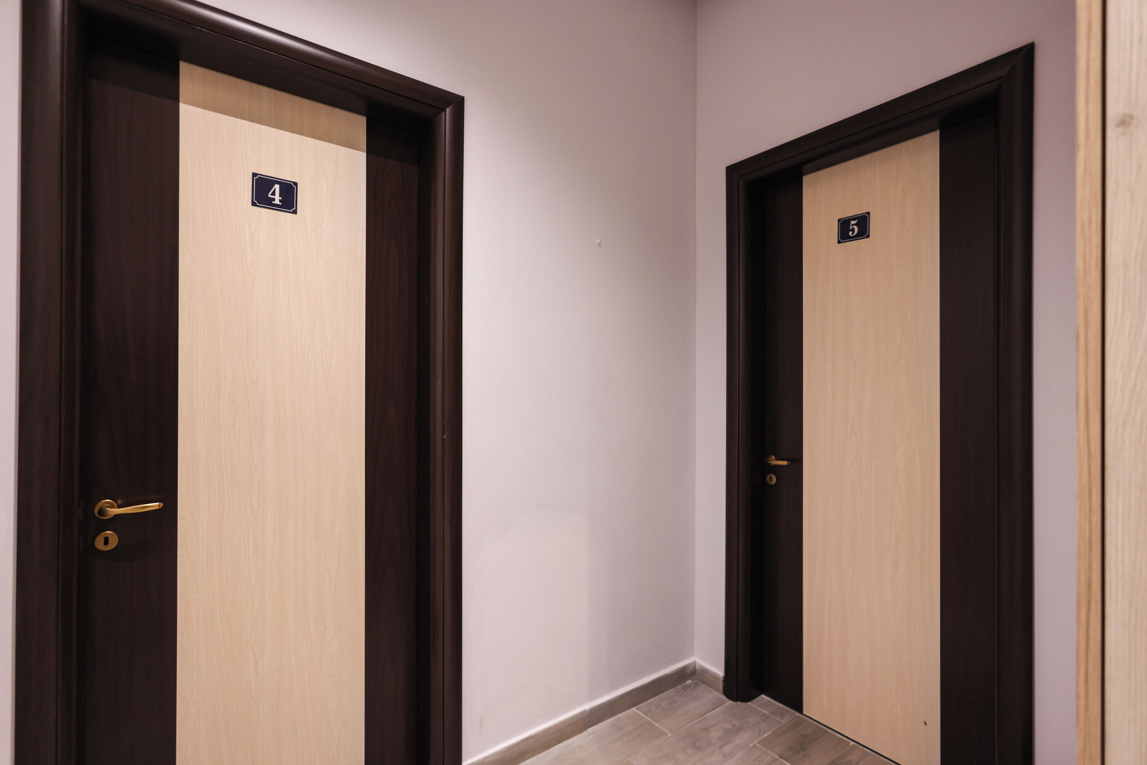 Dos puertas con los números 4 y 5, marcos de madera y una pared de color claro.