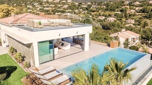 A modern house with a swimming pool, a patio with lounge chairs, and a view of a hilly landscape. - Villa Les Oiseaux Du Paradis Cavalaire-sur-mer (Cavalaire-sur-Mer)