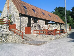 A stone building with a sloped roof, a staircase, and outdoor seating. - Cider Cottage - Near Lyme Regis (Axminster)