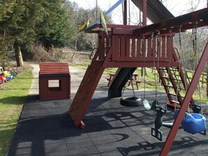 A playground with a slide, swing set, and a small table. - Cider Cottage - Near Lyme Regis (Axminster)