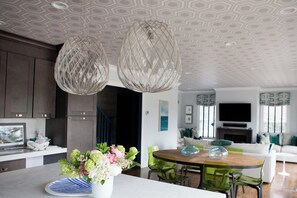 A modern kitchen with a dining area, featuring a central island with a vase of flowers, pendant lights, and a patterned ceiling. - Marion HOUSE - Village, Large Deck, Close to Tabor (Marion)