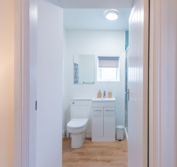 A compact bathroom with a toilet, sink, and mirror.