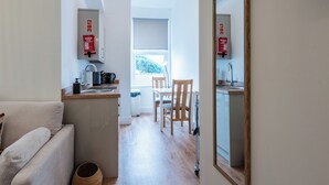 A compact kitchen with a dining area, a sofa, and a mirror. - Glan Neigr by Guestz (Rhosneigr)