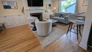 Ein Wohnzimmer mit Kamin, Flachbildfernseher, einer Couch, einem Couchtisch und einem Essbereich mit Stühlen.