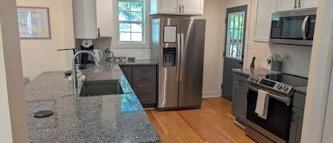 Una cocina moderna con encimeras de granito, electrodomésticos de acero inoxidable y suelo de madera.