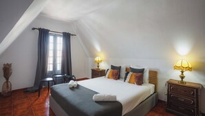 A bedroom with a bed, bedside tables, a lamp, a window with curtains, and a small table.