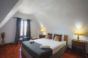 A bedroom with a bed, bedside tables, a lamp, a window with curtains, and a small table.