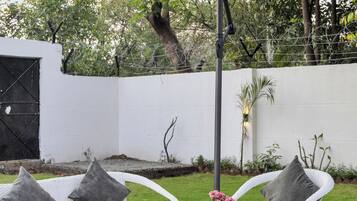 Un patio con muebles de mimbre, una sombrilla a rayas y una pared blanca al fondo.