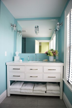 A bathroom with a white vanity, a large mirror, and a window with blinds. - New Marion renovated, bright, cozy home! (Marion)