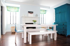 A dining area with a white table, blue chairs, a bench, a blue cabinet, and a fireplace with decorative items. - New Marion renovated, bright, cozy home! (Marion)