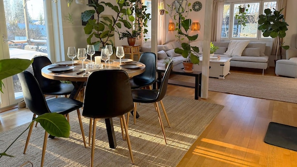A dining area with a round table, chairs, and a large plant. - Villa Bee Mehiläinen (Vantaa)