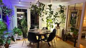 A dining area with a round table, chairs, and potted plants. - Villa Bee Mehiläinen (Vantaa)