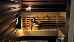 A sauna with wooden benches, a candle, a bottle, and a pot. - Villa Bee Mehiläinen (Vantaa)