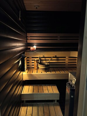 A sauna with wooden benches, a candle, a bottle, and a pot.