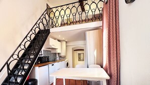 Eine kompakte Küche mit Mikrowelle, Spüle und Waschmaschine, ein Essbereich mit Tisch und Stühlen sowie eine Treppe mit aufwendiger Geländerarbeiten.