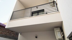 A modern building with a balcony, a door, and an air conditioning unit.