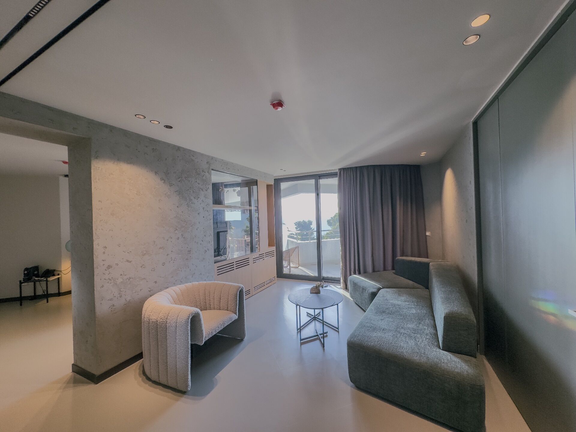 Una sala moderna con un sofá, un sillón y una mesita redonda.