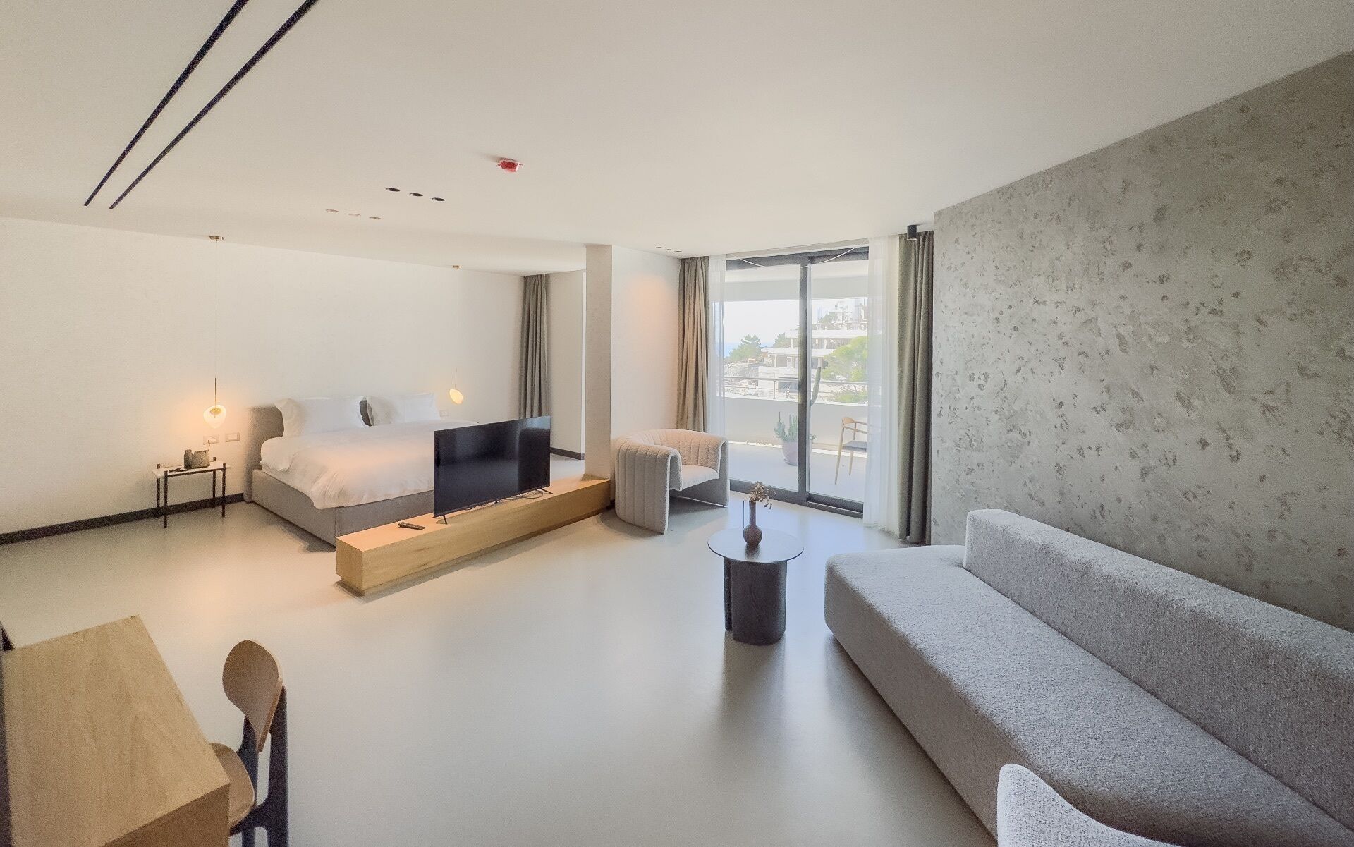 Une chambre d’hôtel moderne équipée d’un lit, d’un canapé, d’une petite table et d’un téléviseur.