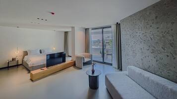 Une chambre d’hôtel moderne, équipée d’un lit, d’un canapé, d’une petite table et offrant une vue sur l’extérieur.