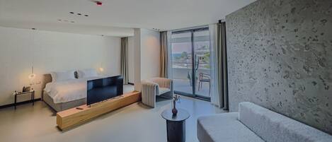 Una habitación de hotel moderna con cama, sofá, una mesita y vistas al exterior.