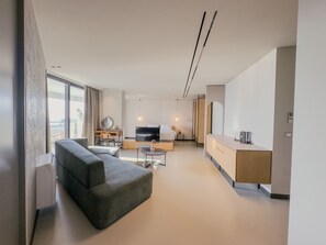 Una sala de estar moderna con sofá, televisor, comedor y mostrador de cocina.