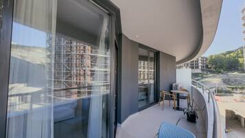 Un balcon avec une table et des chaises, un pot de fleurs et une vue sur un immeuble en construction.