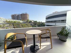 A balcony with two chairs and a table, overlooking a building under construction and a modern building. - Zins Luxury Rooms (Durrës)