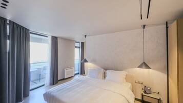 Une chambre d’hôtel moderne avec un grand lit, une table de chevet avec un téléphone et une vue sur un balcon.