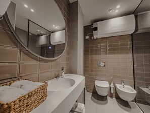 A modern bathroom with a large mirror, a bathtub, a bidet, and a sink. - Zins Luxury Rooms (Durrës)